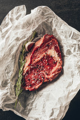 Fototapeta na wymiar top view of raw meat steak and rosemary on baking paper in kitchen