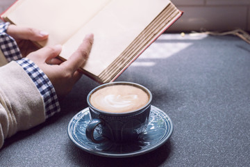 Woman of hands holding hot cup of coffee latte near window morning light.Copy space.