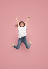 I am happy. Mid-air shot of pretty smiling young woman jumping and gesturing against pink studio background. Runnin girl in motion or movement. Human emotions and facial expressions concept
