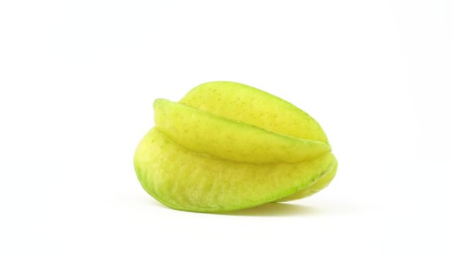 One whole carambola fruit rotating on the turntable isolated on the white background. Close up. Macro.