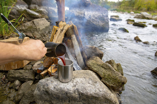 Aromatic and hot coffee on the fire. Bonfire and thermo mugs. Bonfire on the river bank.