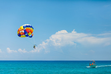 Mensen vliegen aan een kleurrijke parachute getrokken door een motorboot