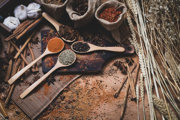 Colorful various spice and herbs in wood spoon on natural texture burned wood plate.