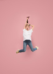 Freedom in moving. Mid-air shot of pretty happy young woman jumping and gesturing against pink studio background. Runnin girl in motion or movement. Human emotions and facial expressions concept