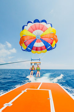 Couple of tourists flying on a multi colored parachute
