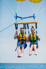 Couple of tourists flying on a colorful parachute