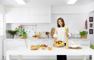 Beautiful Asian woman showing her new kitchen decoration and play with fake fruits and vegetables. Concept to modern housewife work.