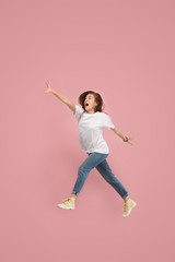 Fototapeta na wymiar What is there interesting in the distance. seeking pretty happy young woman jumping and grabbing against pink studio background. Runnin girl in motion or movement. Human emotions and facial
