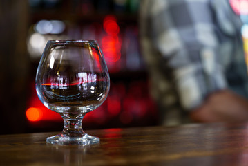 one wine glass stands on the table in the cafe on the background of a waiter and interior