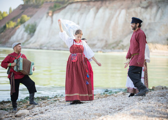 Young people in Russian national costumes dancing, playing accordion