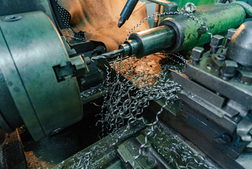 spiral steel shavings fall to floor near the lathe in plant of metal industry. Close-up