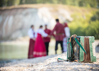 Shot of the accordion, on the background of a group of young people in Russian national costumes