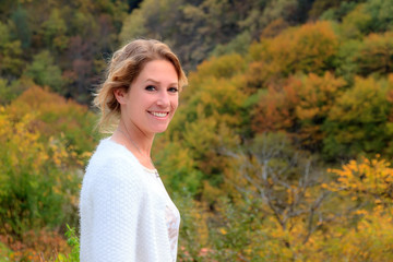 Beautiful portrait of a gorgeous young woman in the mountains of the Rila national park in Bulgaria with vibrant autumn colors in the forest