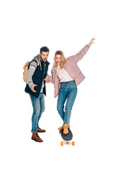 handsome young man with backpack holding hand on beautiful smiling girl riding longboard isolated on white