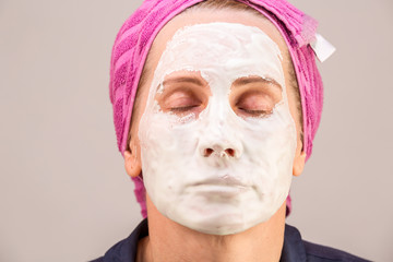 girl with facial mask looking at camera over white background. Cosmetic procedure. Beauty spa and cosmetology.