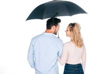 back view of happy young couple holding umbrella and smiling each other isolated on white