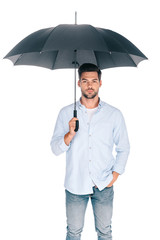 handsome bearded young man holding umbrella and looking at camera isolated on white