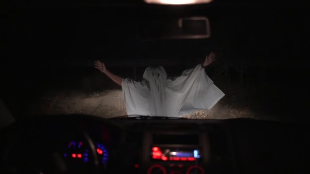 Ghost at dusk on a road in low light, throwing himself to the windshield