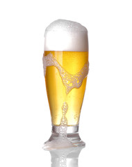 A glass of light beer in a glass with foam on a white isolated background