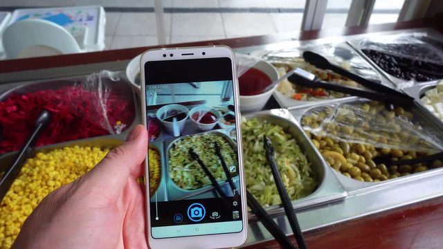 Food photo. A person trendy blogger photographs rows with food in a salad buffet.