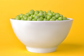Green fresh pea in a white bowl on a bright trendy yellow background