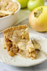 A traditional American apple pie decorated with stars and sugar, apples and cinnamon on a light background.