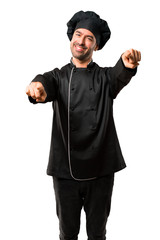 Chef man In black uniform points finger at you while smiling on isolated white background