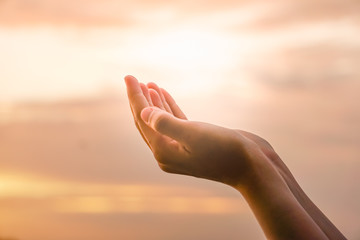 Woman hands place together like praying in front of nature green  background.