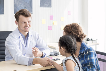 Fototapeta premium Pediatrician (doctor) man examining child with stethoscope at surgery .Mother Caucasian and kid smiling in hospital room.Copy space.