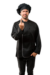 Chef man In black uniform making horn gesture. Negative expression on isolated white background