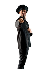 Chef man In black uniform points finger at you while smiling on isolated white background