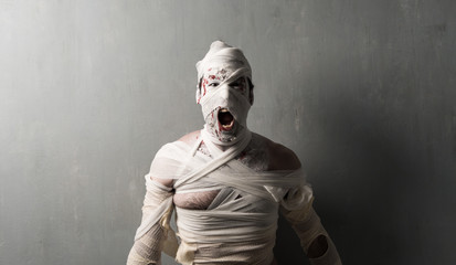 Terrorific mummy screaming on textured wall background.  Halloween holidays