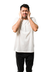 Fototapeta premium Young man with white shirt covering both ears with hands. Frustrated expression on isolated white background