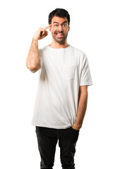 Young man with white shirt making the gesture of madness putting finger on the head on isolated white background