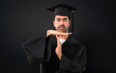 Man on his graduation day University making stop gesture with her hand to stop an act on black background
