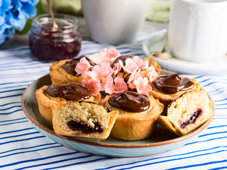 Cakes with frangipane, cherry jam and chocolate frosting. Romantic table setting with flowers. Mother's day card