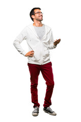 A full-length shot of a Man with glasses and listening music posing with arms at hip and laughing on white background