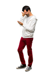 A full-length shot of a Man with glasses and listening music covering eyes by hands. Surprised to see what is ahead on white background