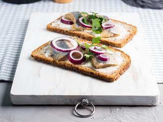 Danish open sandwich smorrebrod with salted herrings, red onion, butter. Traditional snack