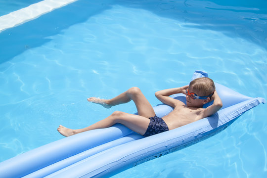 a boy is swimming on a mattress in the pool in the Villa