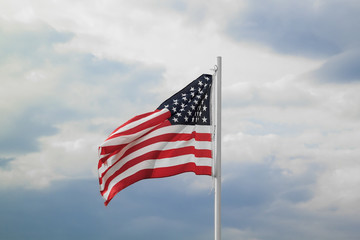 Obraz premium American flag on a blue sky with clouds background