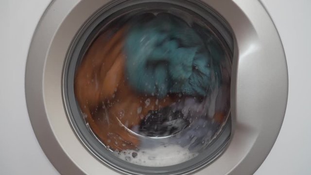 Washing Machine with colorful clothes working. Close up