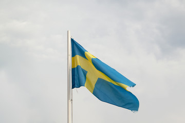 Flag of Sweden on a blue sky with clouds background