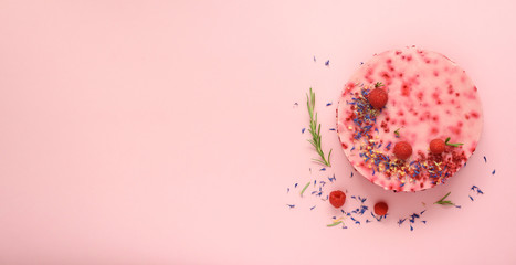 Delicious raspberry cake with fresh berries, rosemary and dry flowers on pink background. Copy space for your text. Vegetarian, vegan food concept