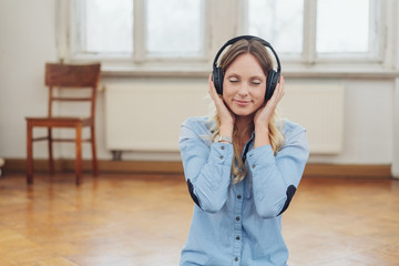frau hört musik mit geschlossenen augen in einer leeren wohnung