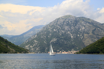 spectacular views of the boat in the middle of the Bay of Kotor and the city of Perast at the foot of the mountain behind