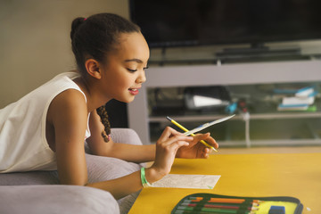 Tween girl drawing with colored pencils in living room