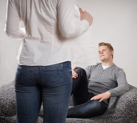 woman taking off blouse while man sitting expectantly on sofa                   