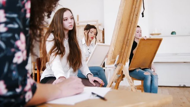 Attractive girls are sitting behind the easel