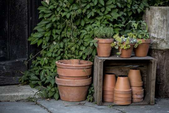 Close up of stacks of terracotta flower pots on a stone floor and wooden box.